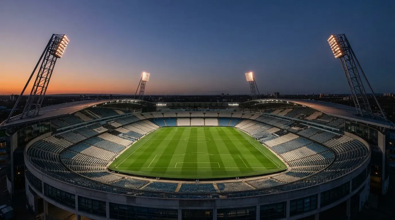 An empty football stadium with floodlight masts at dusk
