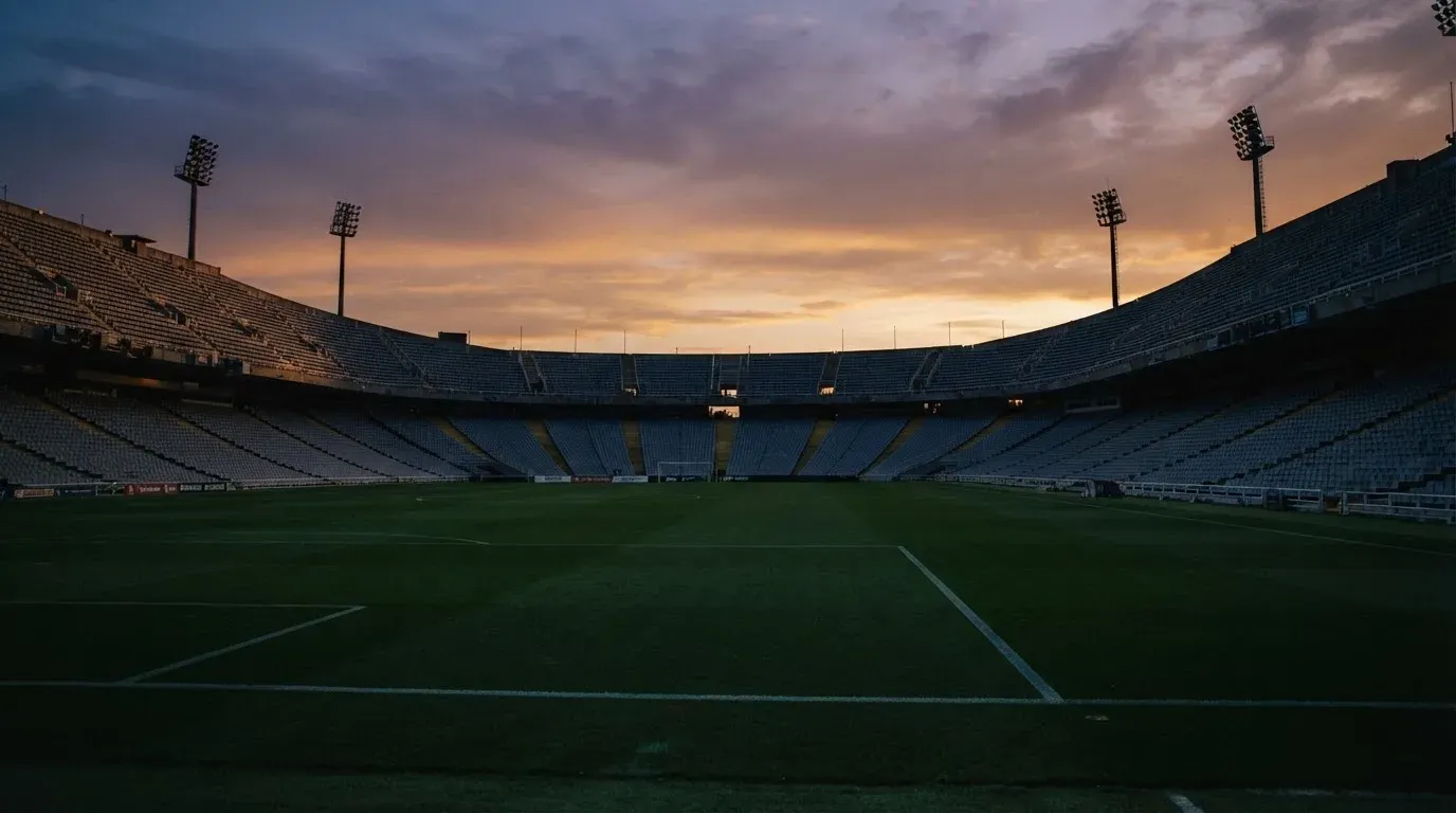 An empty football stadium with floodlight masts at dusk