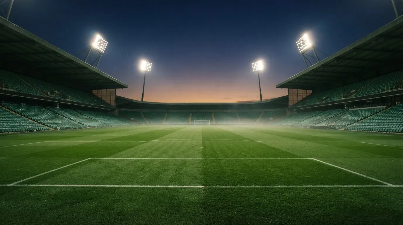 An empty football stadium with floodlight masts at dusk