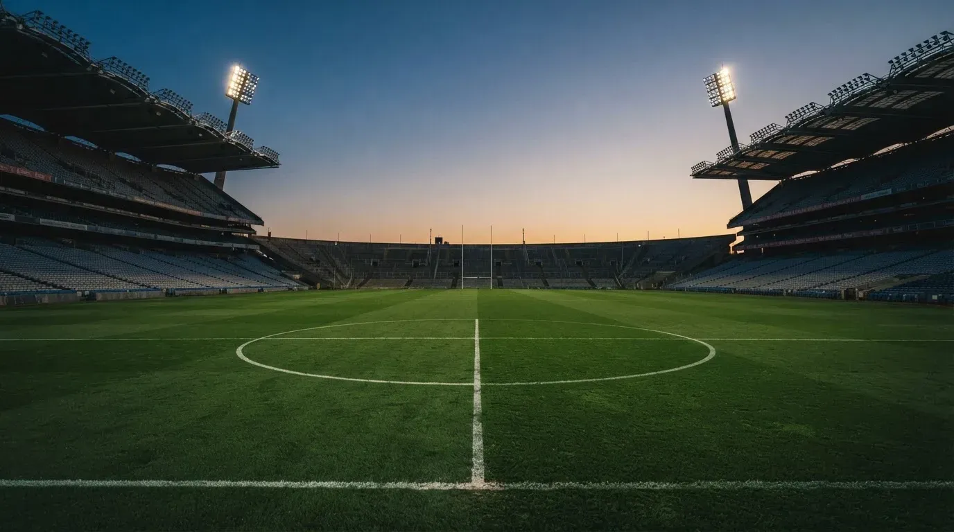An empty football stadium with floodlight masts at dusk