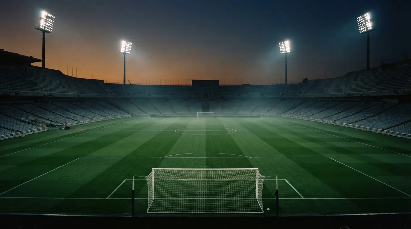 An empty football stadium with floodlight masts at dusk