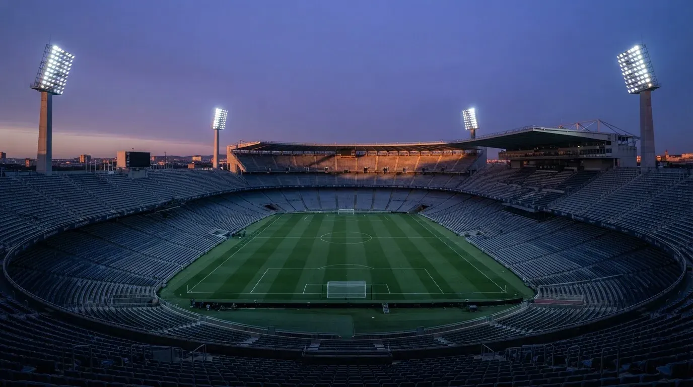 An empty football stadium with floodlight masts at dusk