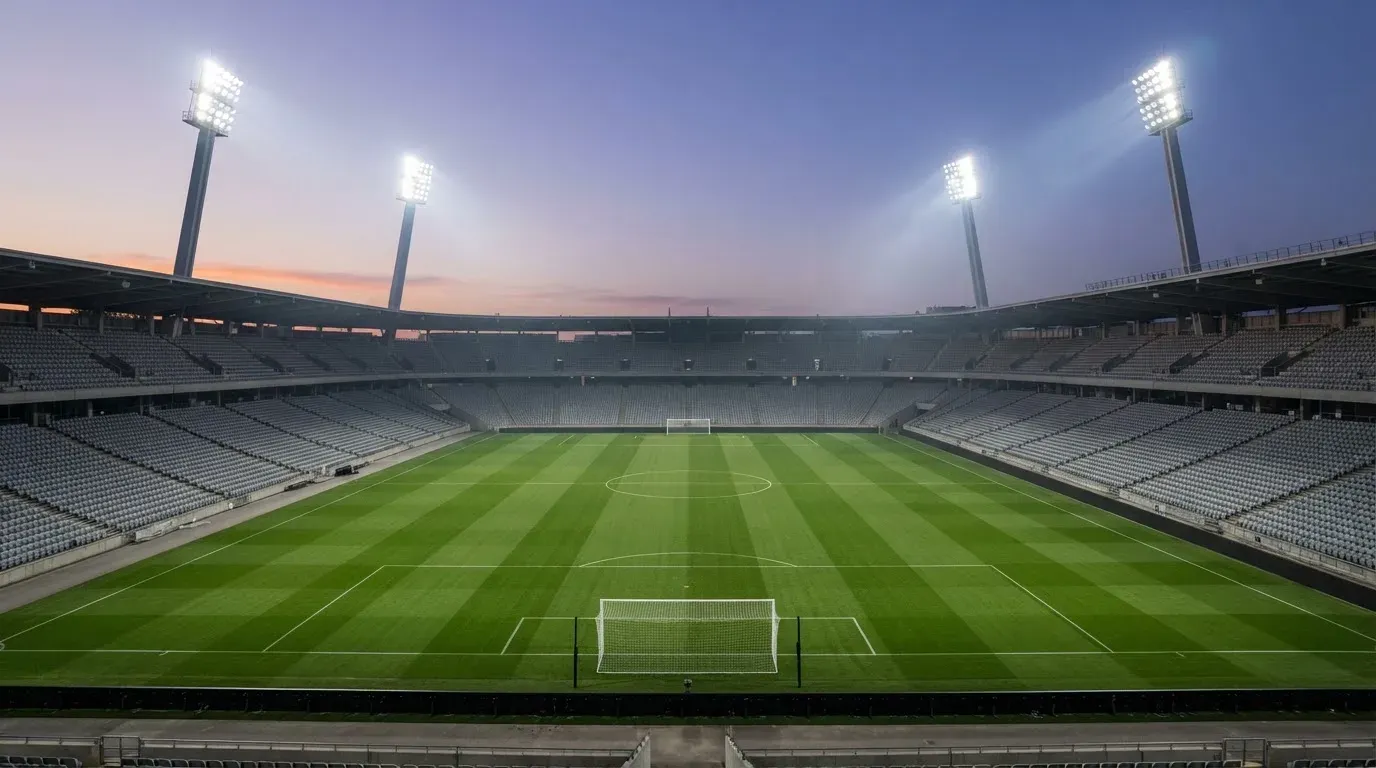 An empty football stadium with floodlight masts at dusk