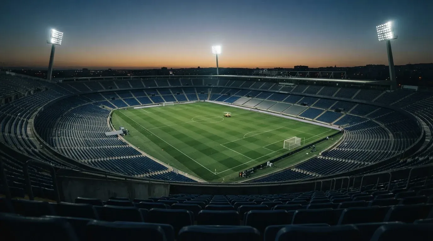 An empty football stadium with floodlight masts at dusk