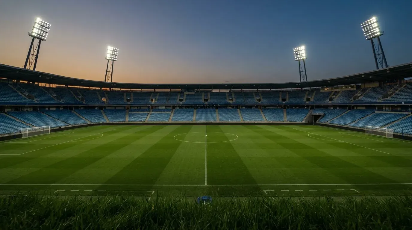 An empty football stadium with floodlight masts at dusk
