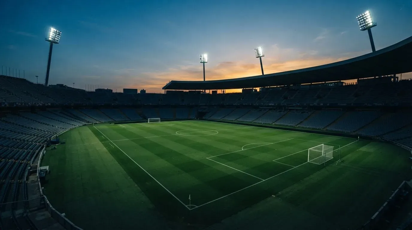 An empty football stadium with floodlight masts at dusk