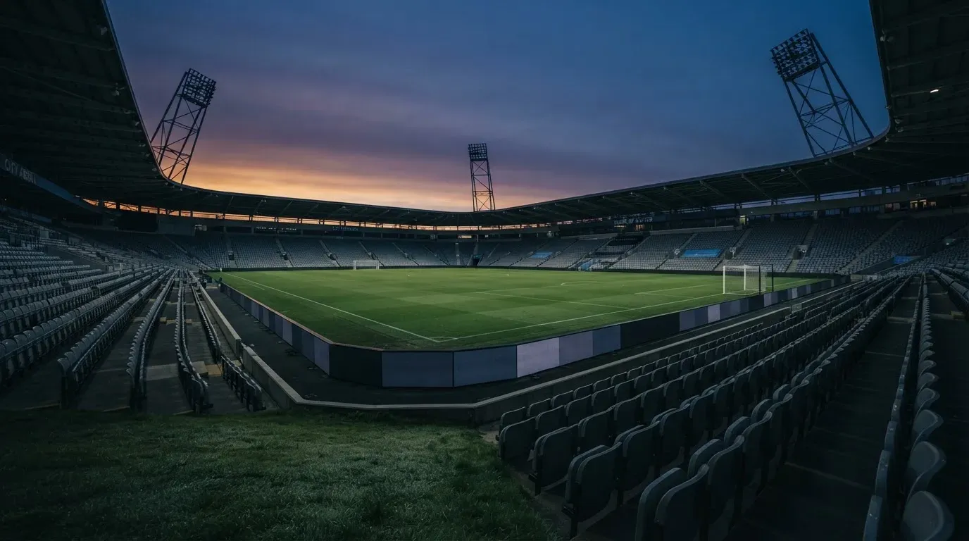 An empty football stadium with floodlight masts at dusk