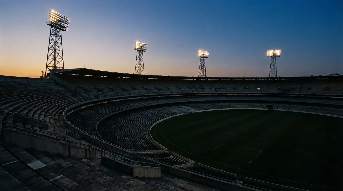 An empty football stadium with floodlight masts at dusk