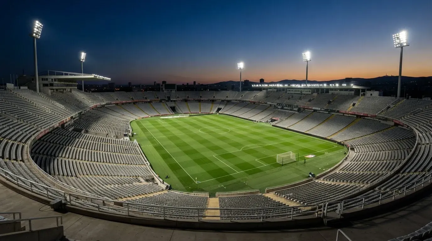 An empty football stadium with floodlight masts at dusk