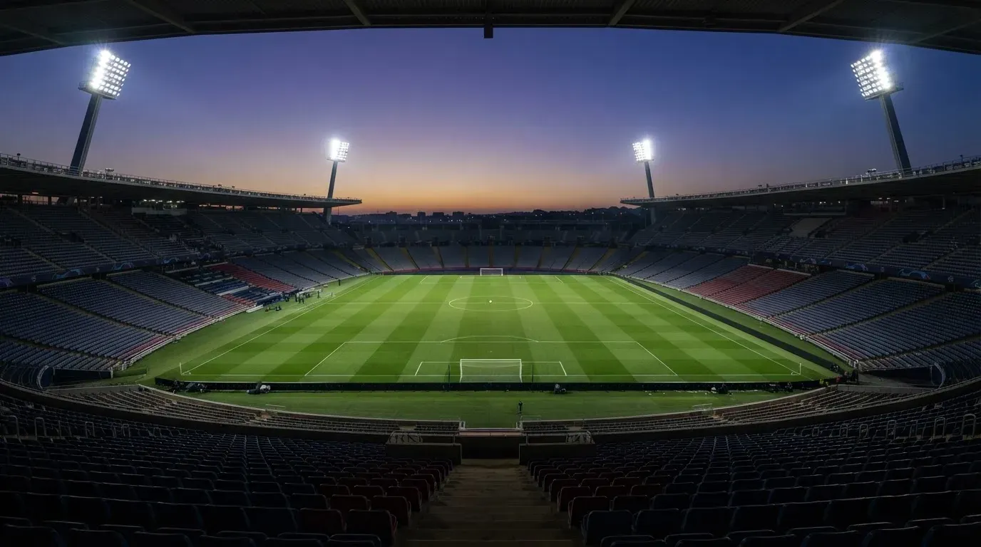 An empty football stadium with floodlight masts at dusk