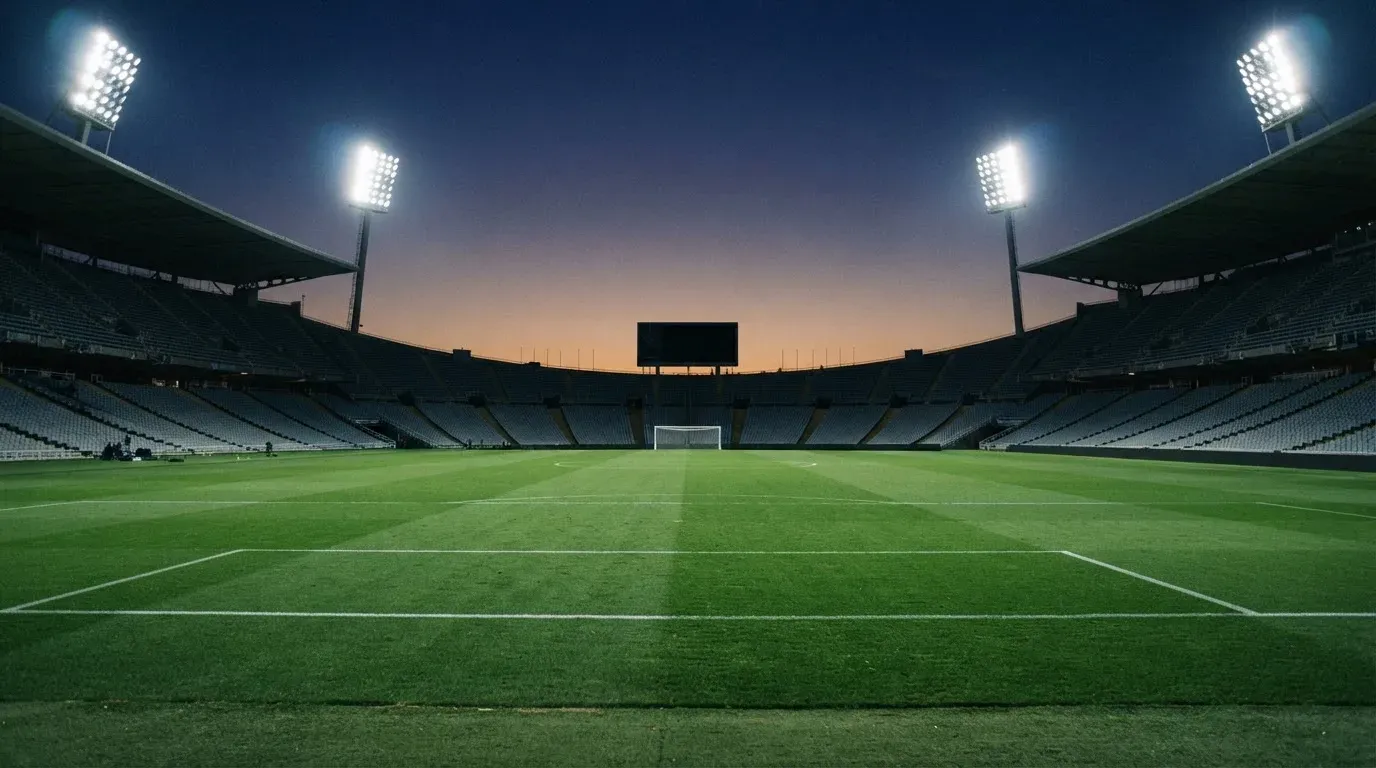 An empty football stadium with floodlight masts at dusk