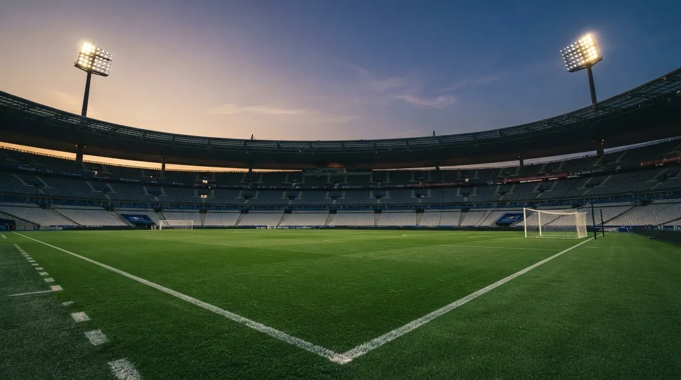 An empty football stadium with floodlight masts at dusk