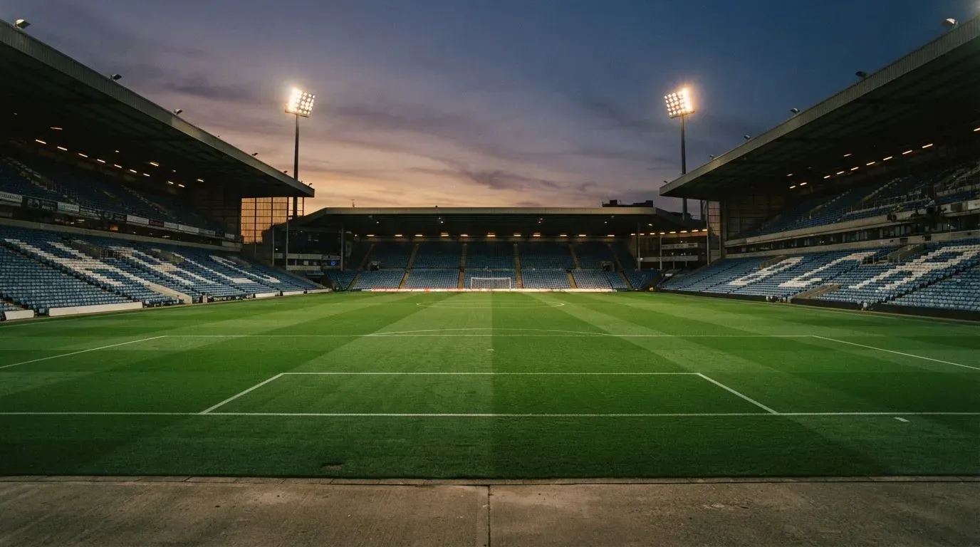 An empty football stadium with floodlight masts at dusk