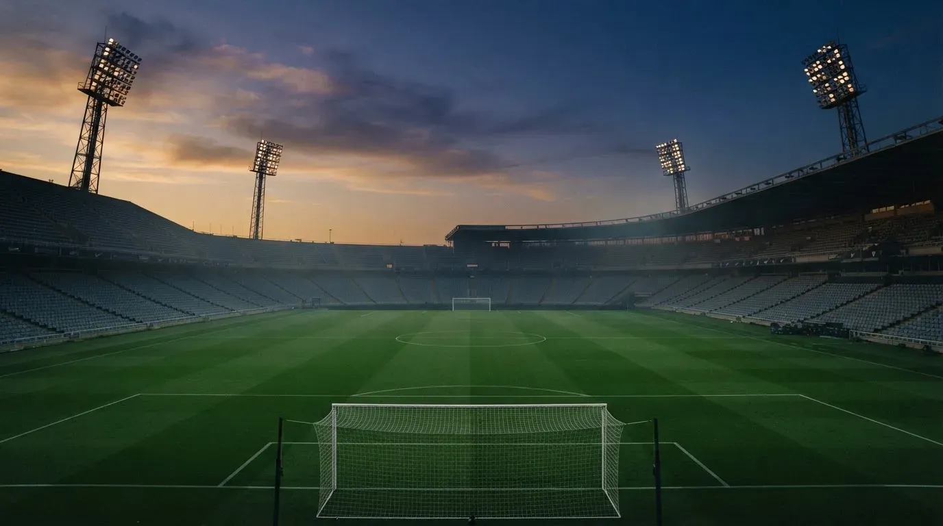 An empty football stadium with floodlight masts at dusk