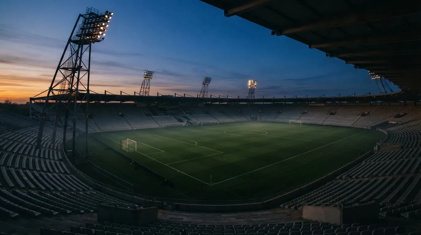 An empty football stadium with floodlight masts at dusk