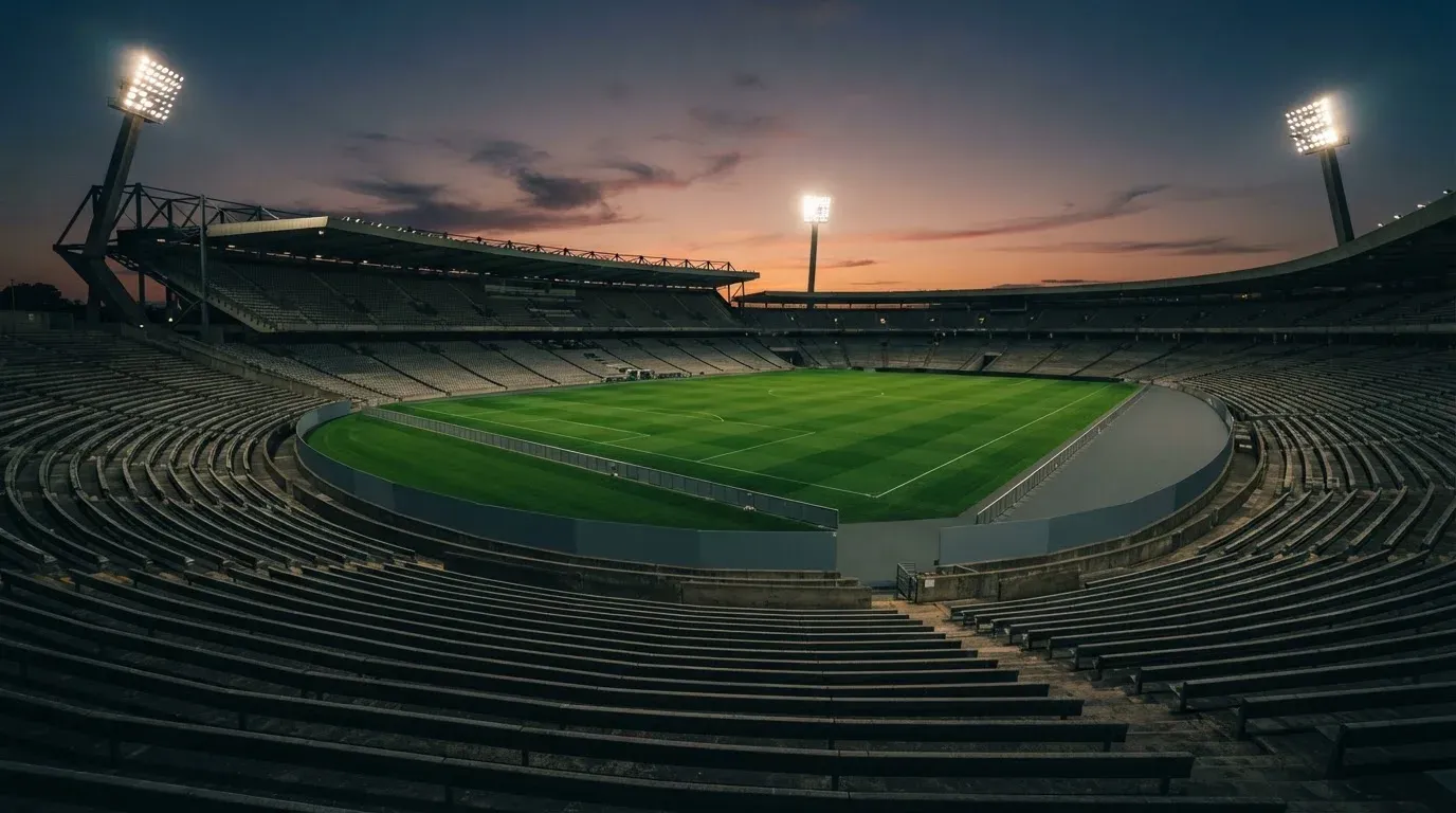 An empty football stadium with floodlight masts at dusk