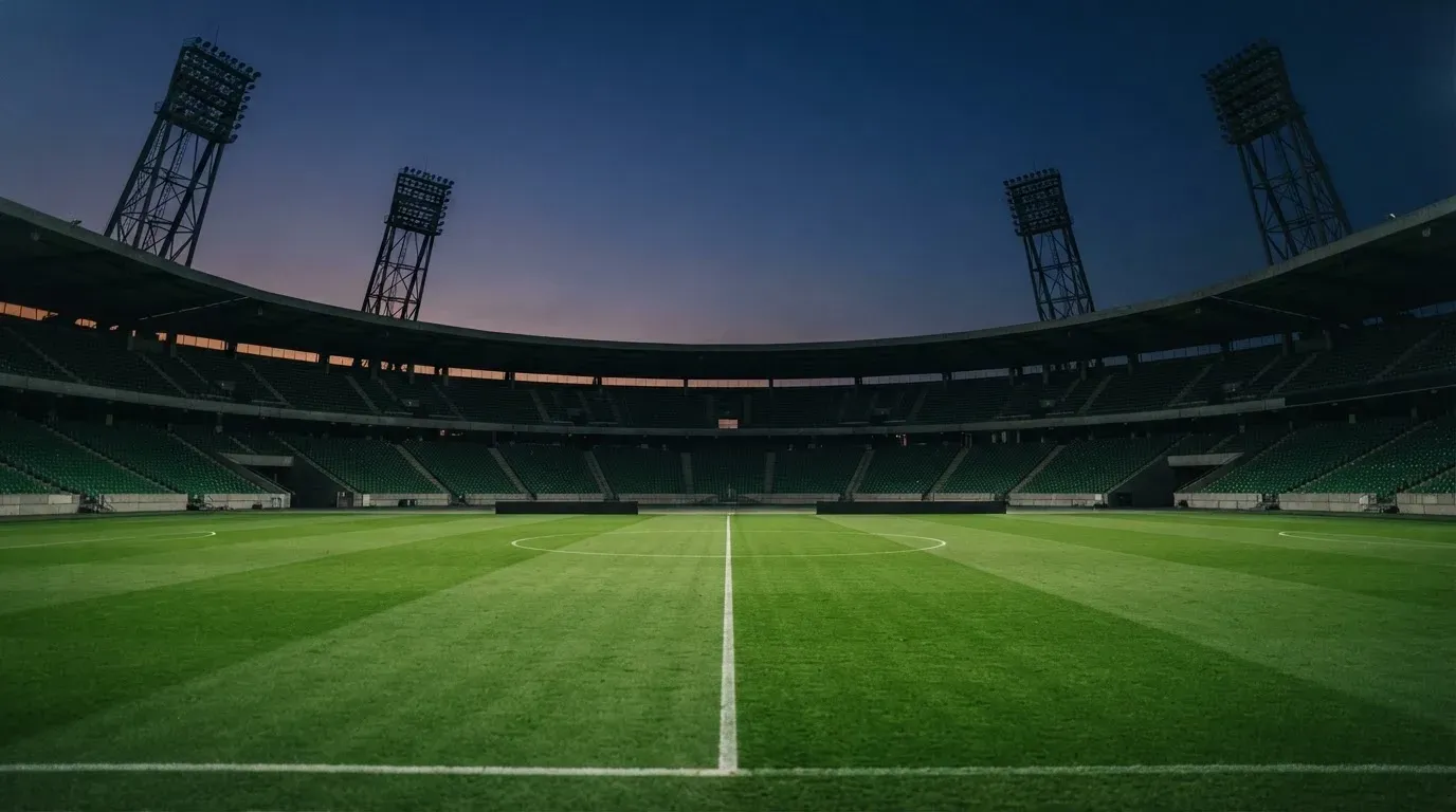 An empty football stadium with floodlight masts at dusk
