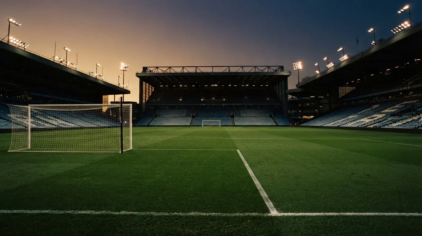 An empty football stadium with floodlight masts at dusk