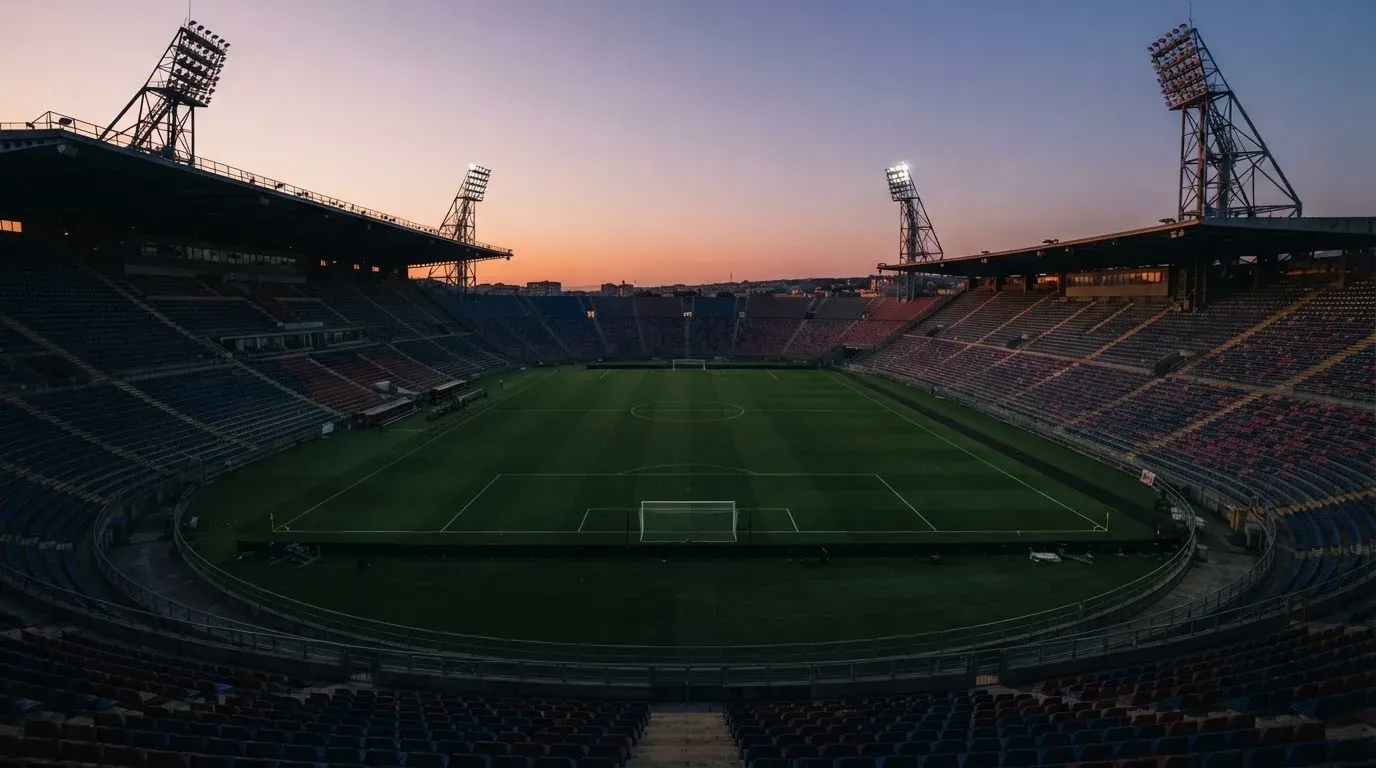 An empty football stadium with floodlight masts at dusk