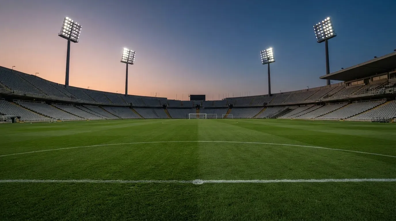 An empty football stadium with floodlight masts at dusk