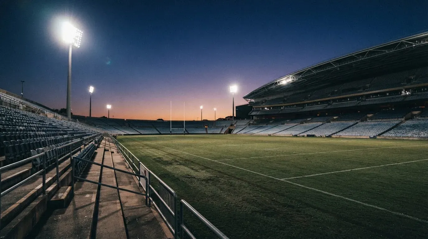 An empty football stadium with floodlight masts at dusk