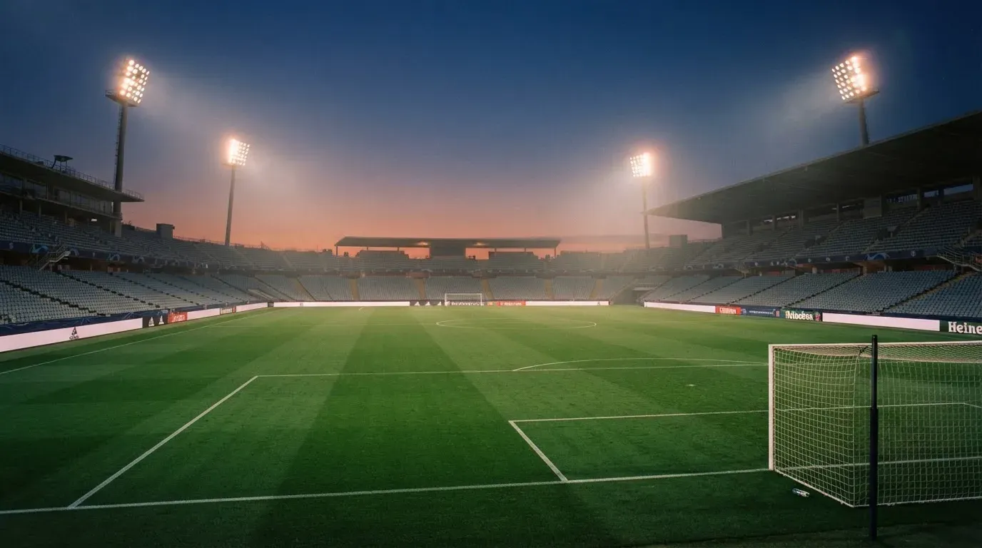 An empty football stadium with floodlight masts at dusk