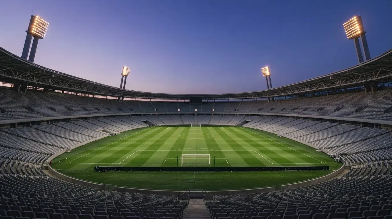 An empty football stadium with floodlight masts at dusk