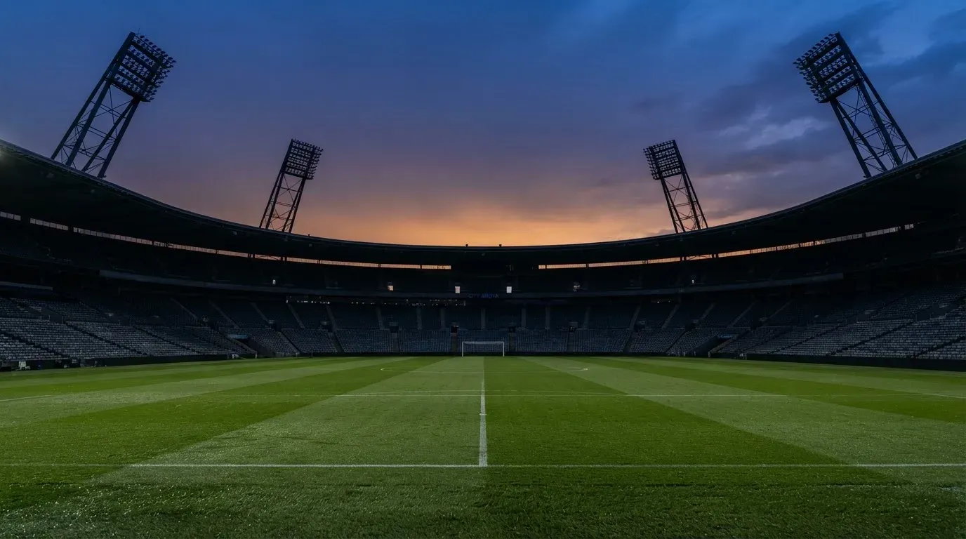 An empty football stadium with floodlight masts at dusk