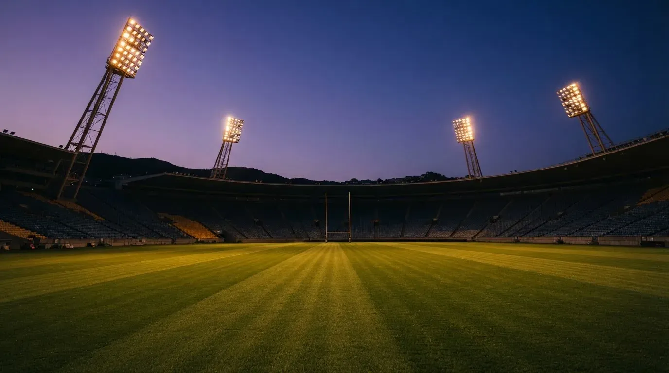 An empty football stadium with floodlight masts at dusk