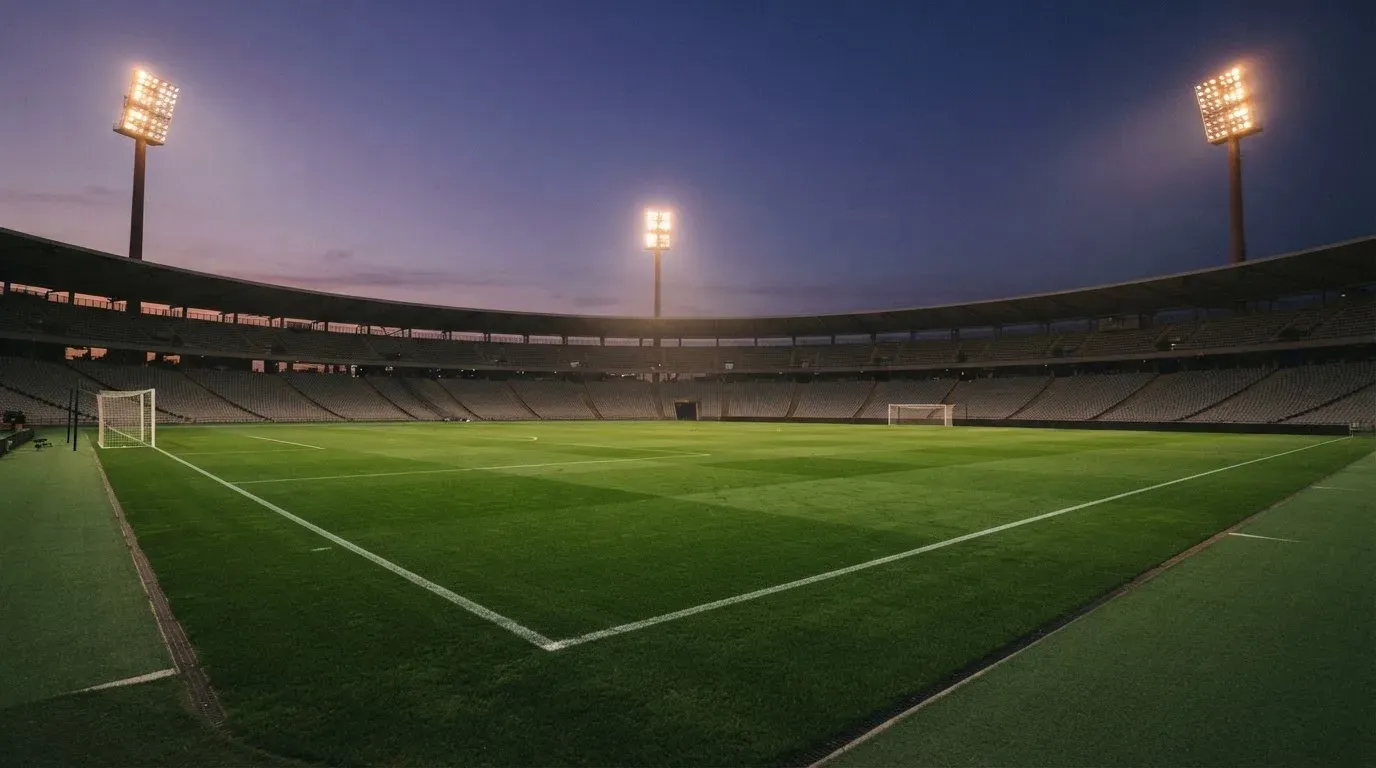 An empty football stadium with floodlight masts at dusk