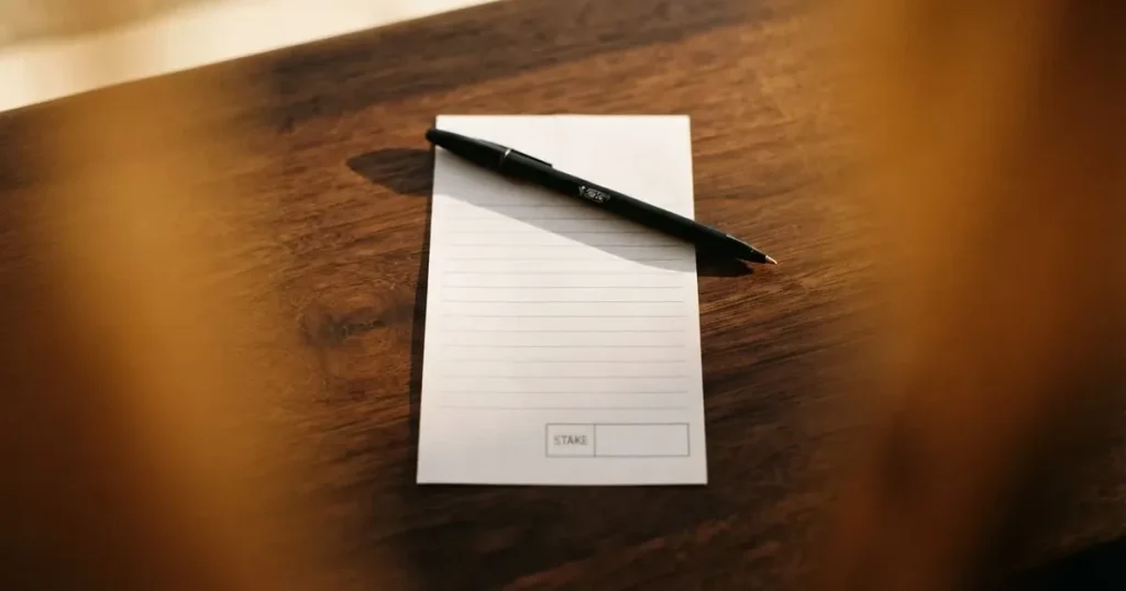 A blank paper betting slip beside a pen on a wooden counter