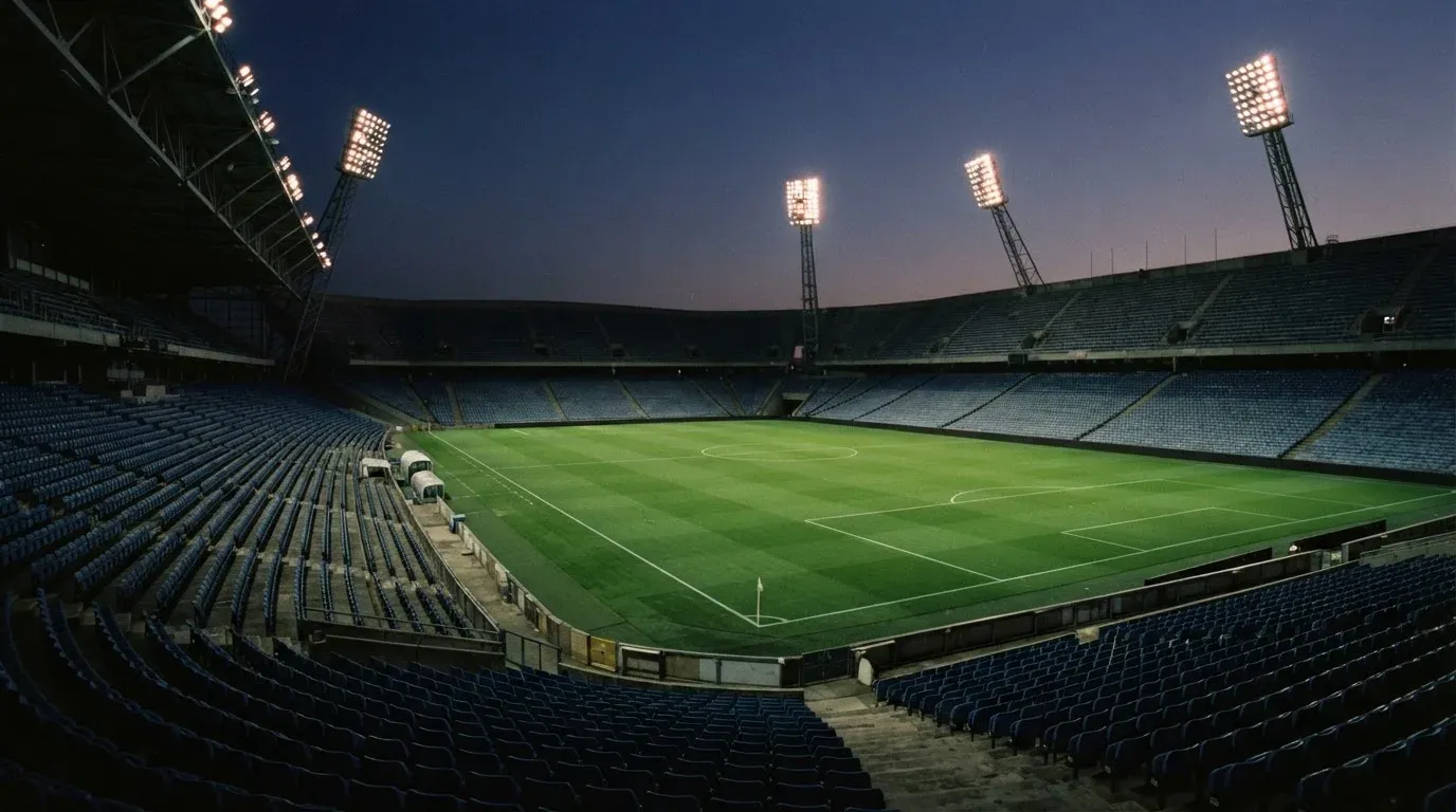 An empty football stadium with floodlight masts at dusk
