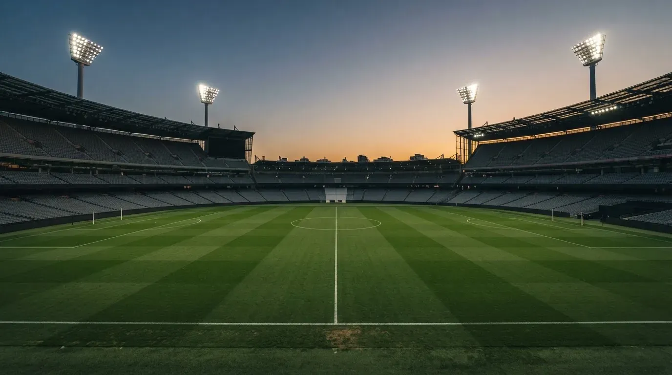 An empty football stadium with floodlight masts at dusk