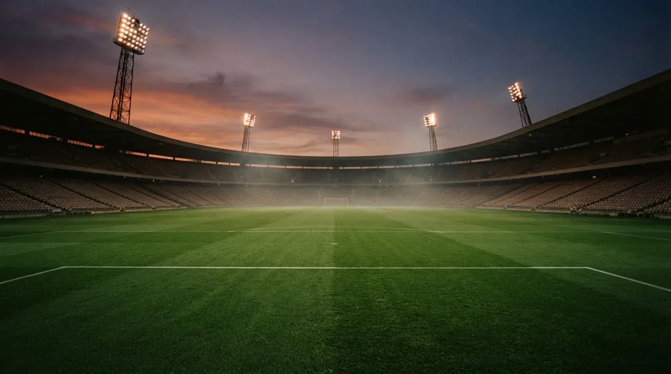 An empty football stadium with floodlight masts at dusk