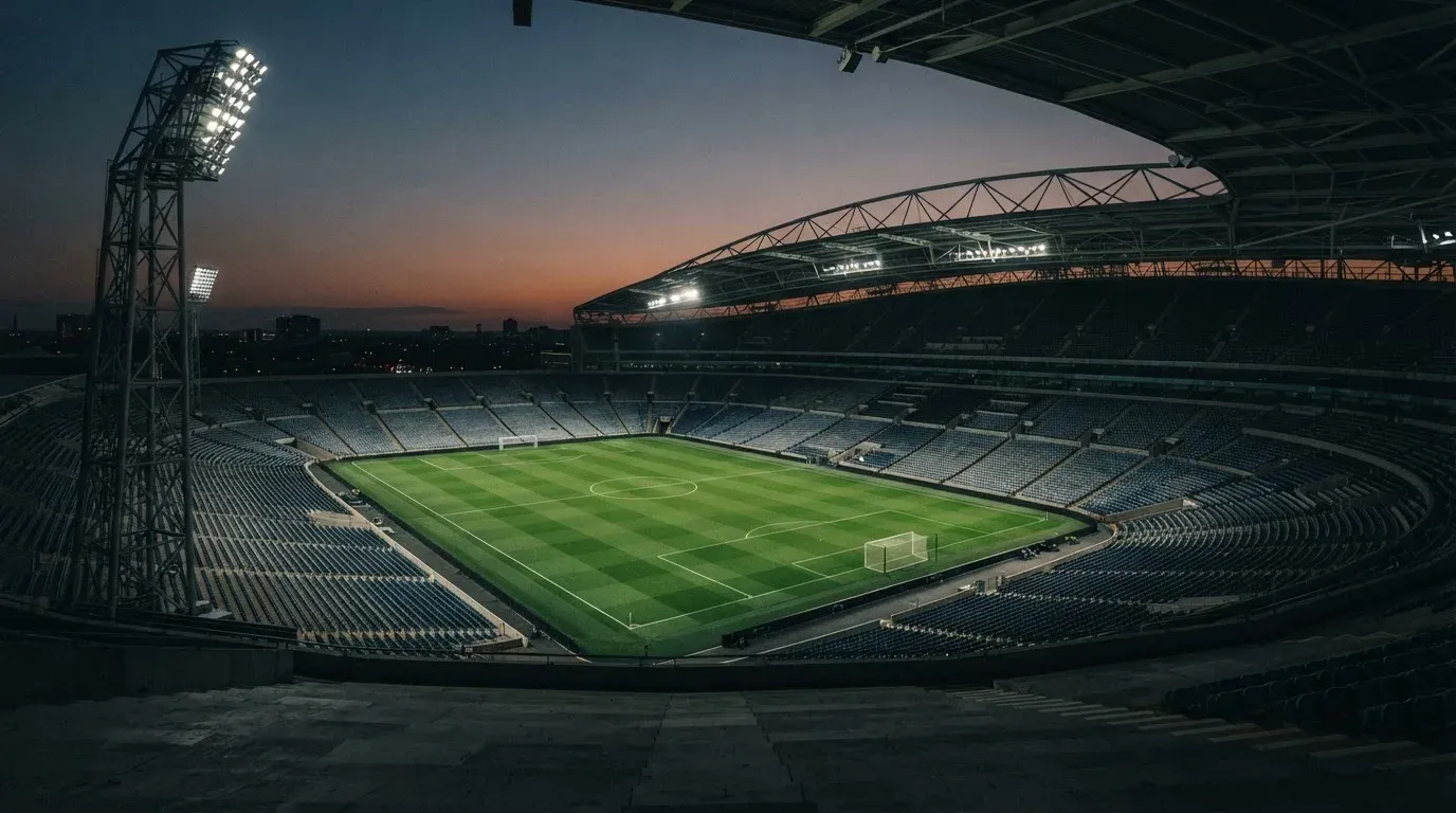 An empty football stadium with floodlight masts at dusk