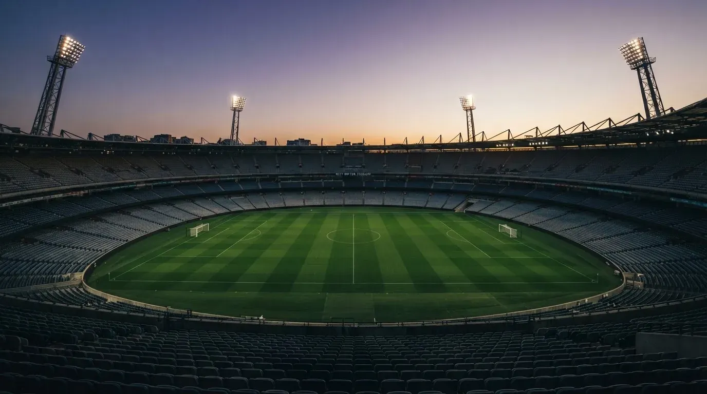 An empty football stadium with floodlight masts at dusk