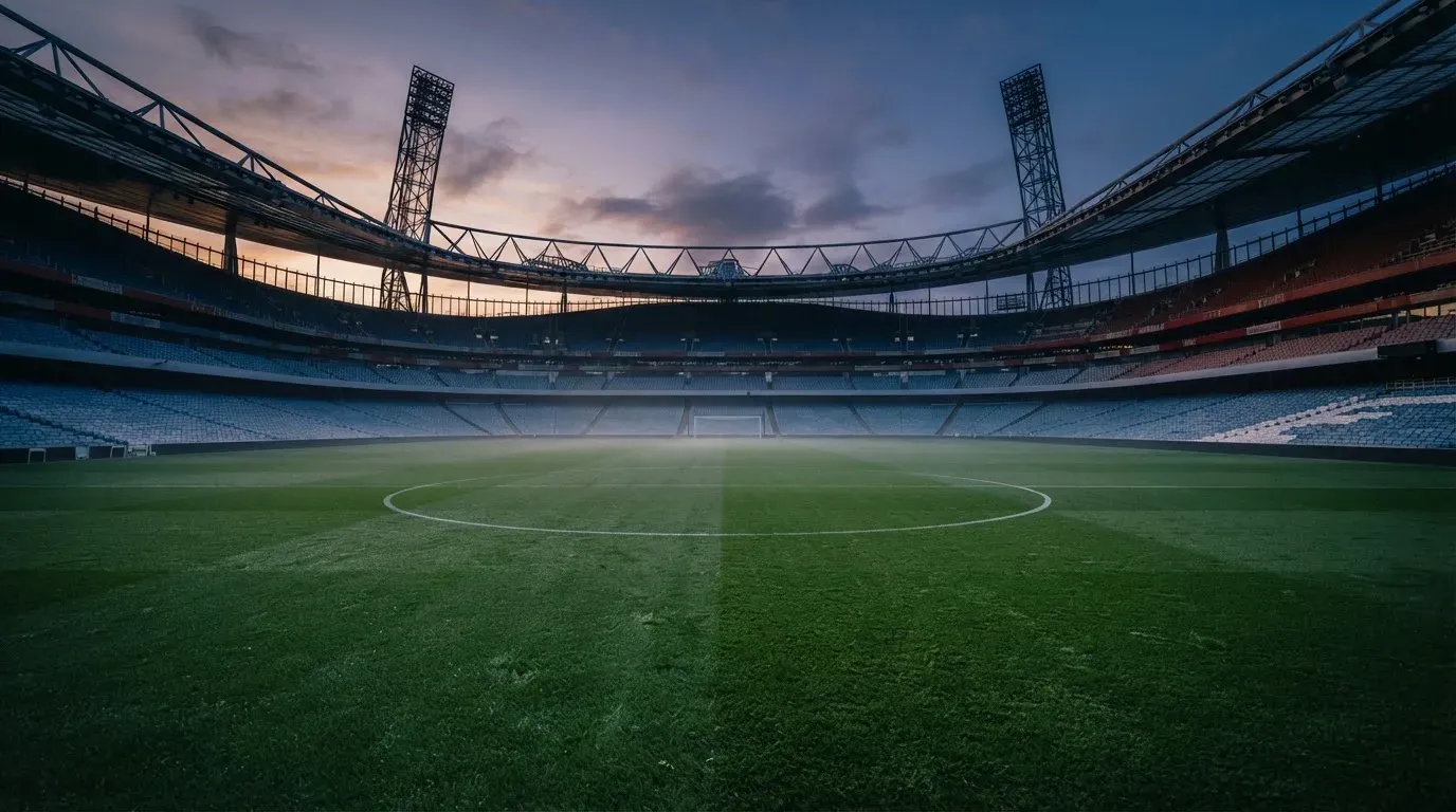 An empty football stadium with floodlight masts at dusk