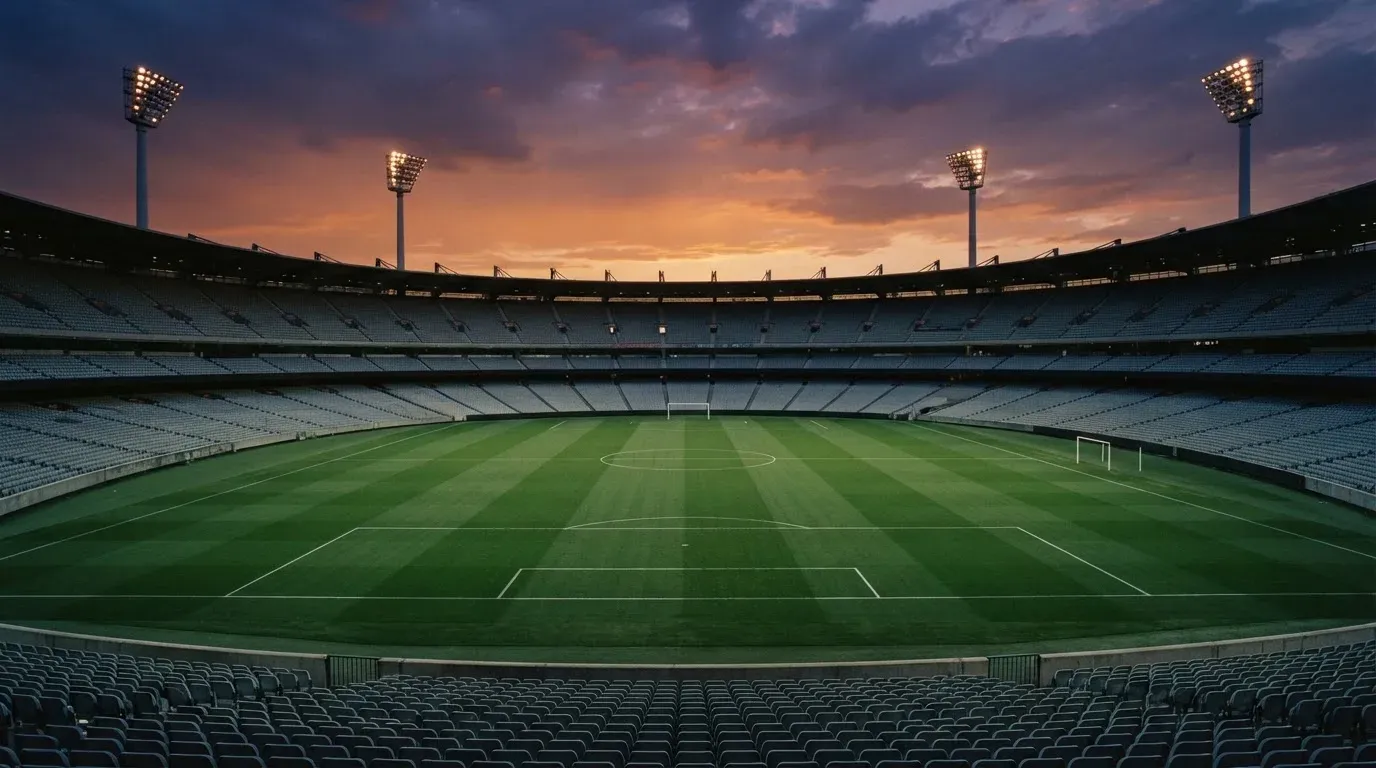 An empty football stadium with floodlight masts at dusk
