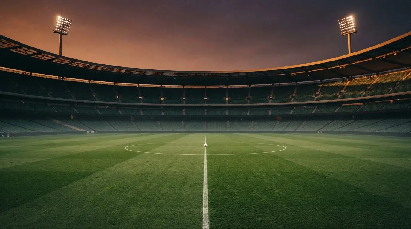 An empty football stadium with floodlight masts at dusk