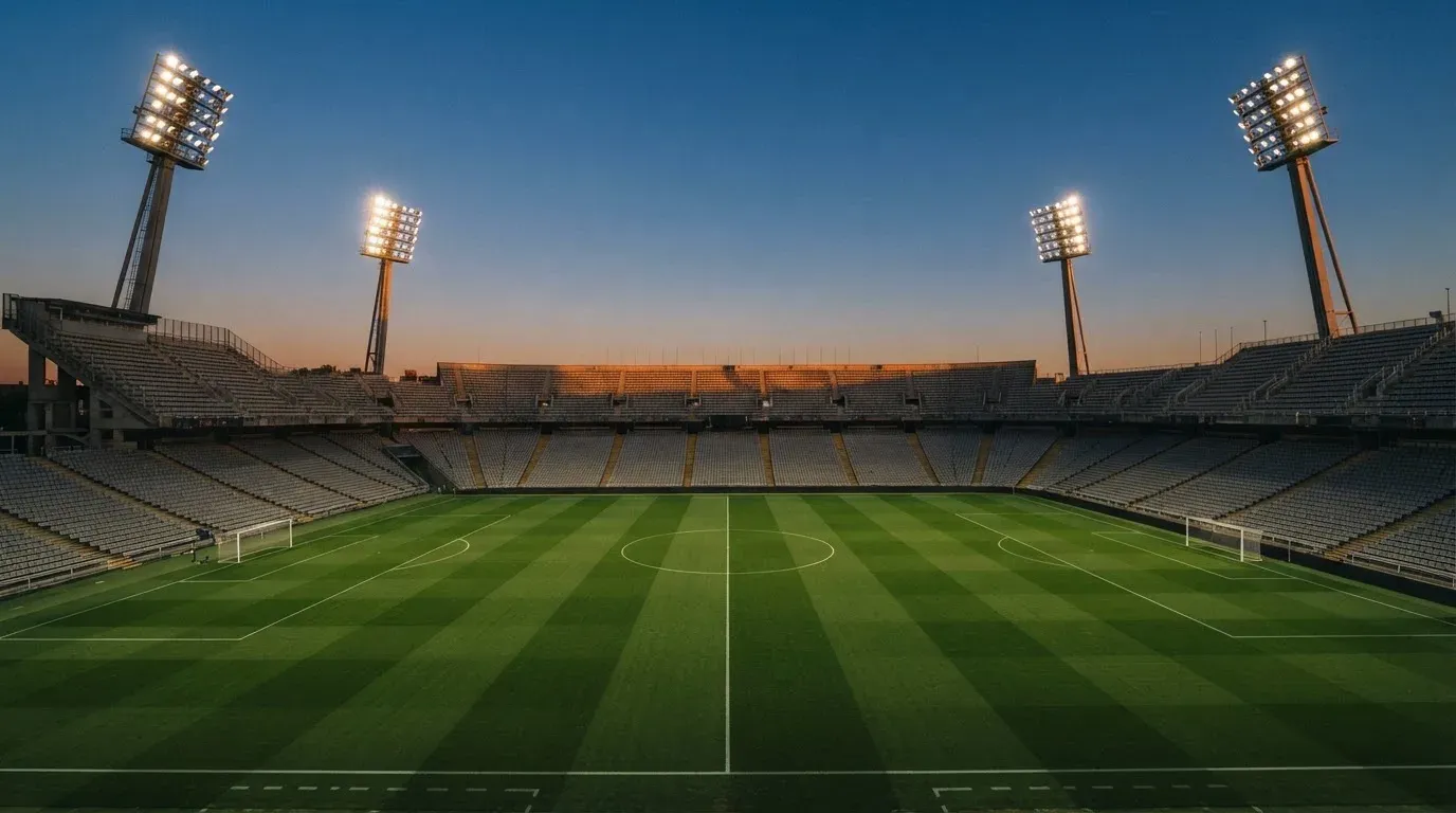 An empty football stadium with floodlight masts at dusk