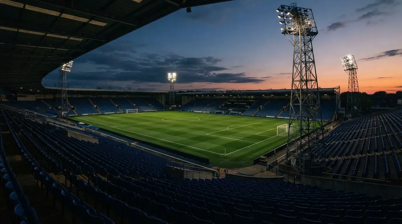 An empty football stadium with floodlight masts at dusk