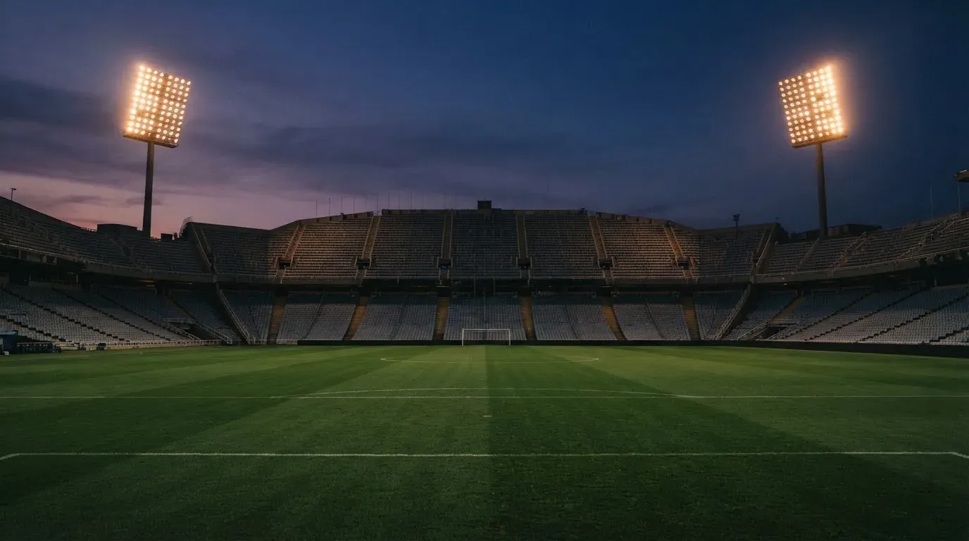 An empty football stadium with floodlight masts at dusk