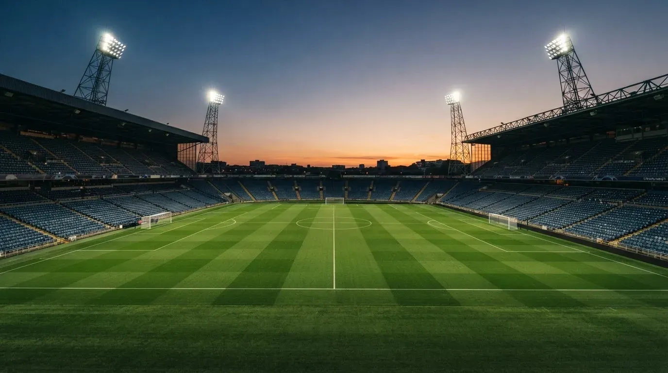 An empty football stadium with floodlight masts at dusk