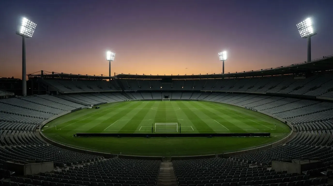 An empty football stadium with floodlight masts at dusk