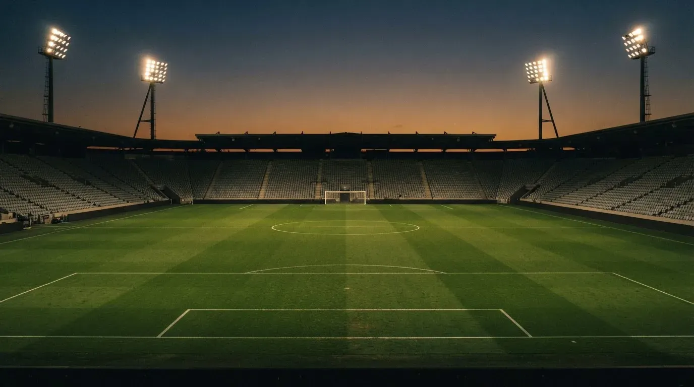 An empty football stadium with floodlight masts at dusk