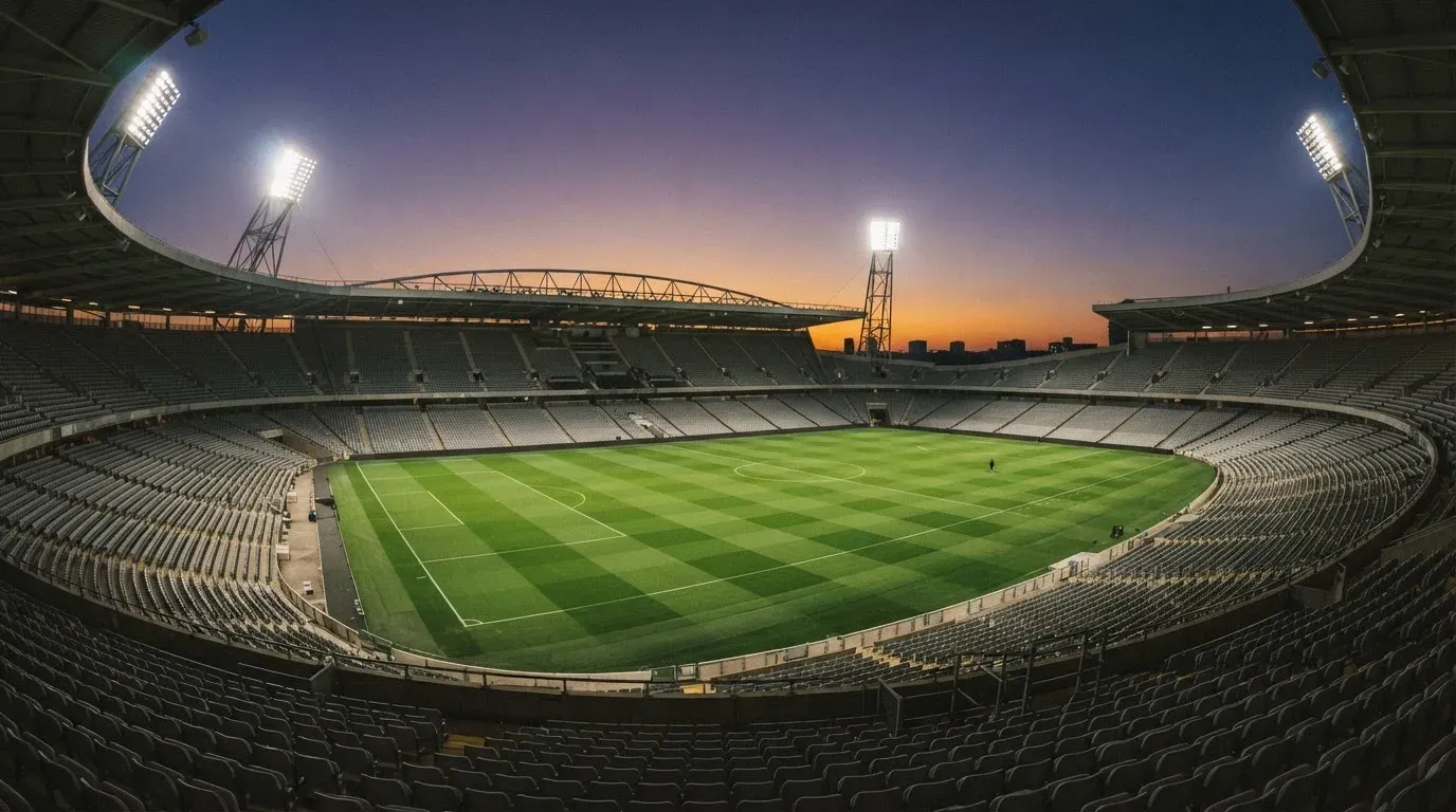 An empty football stadium with floodlight masts at dusk