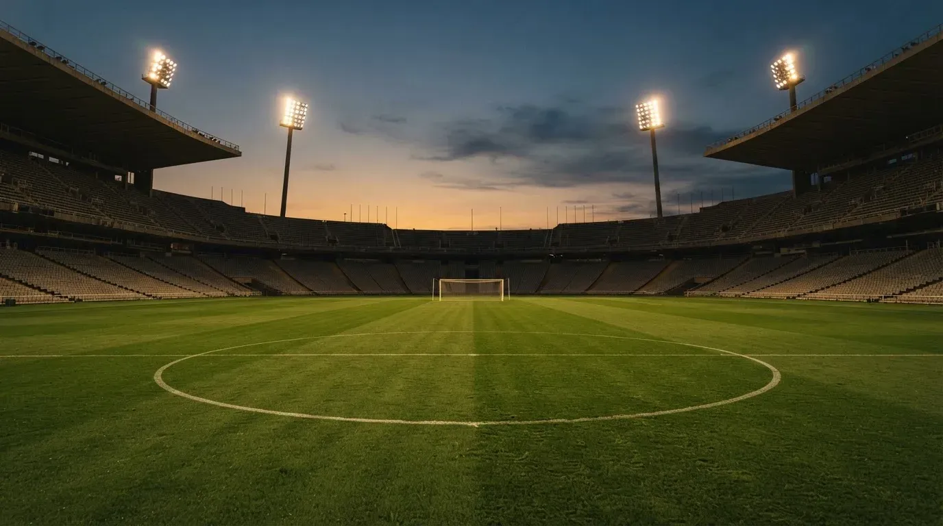 An empty football stadium with floodlight masts at dusk