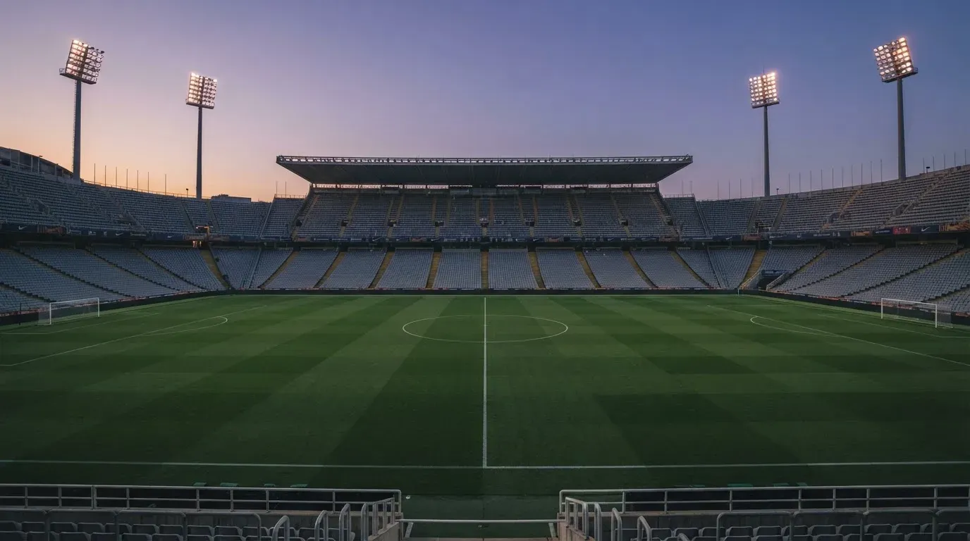 An empty football stadium with floodlight masts at dusk