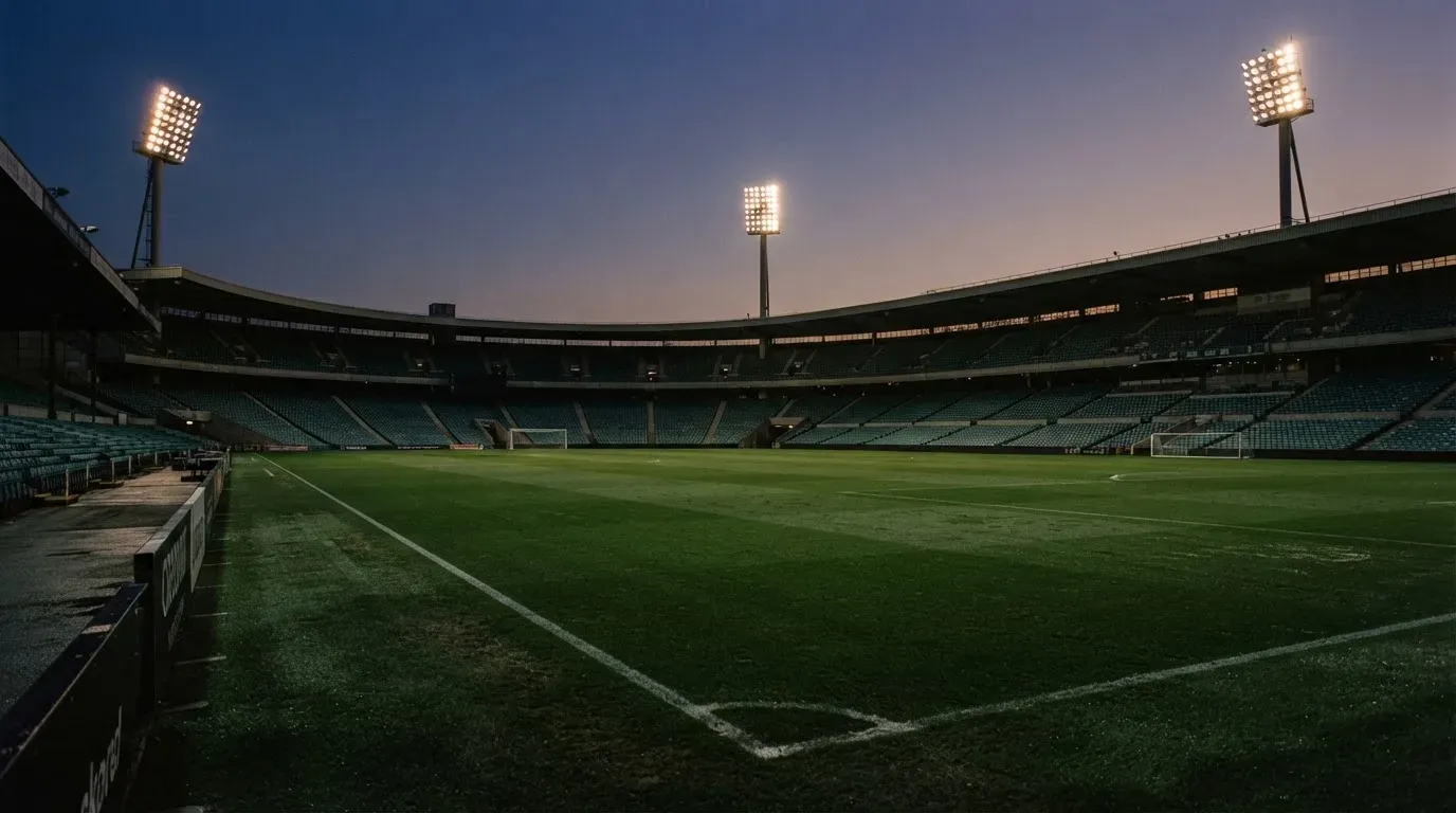 An empty football stadium with floodlight masts at dusk