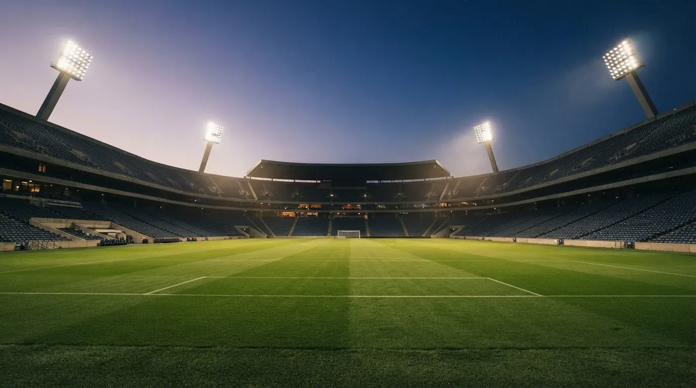 An empty football stadium with floodlight masts at dusk